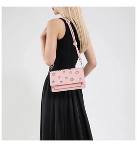 Close-up of pink rectangular crossbody bag with silver eyelets and knot strap detail