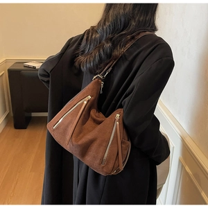 Detail of brown suede shoulder bag with parallel metal zippers and long leather pullers