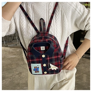 Detail of shirt-style plaid mini backpack featuring embroidery and bow-tie collar design