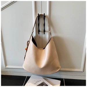 Detail of beige hobo shoulder bag with textured faux leather and wooden bead pendant