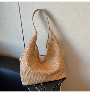 Detail of khaki woven hobo bag with textured crossbody strap and minimalist design