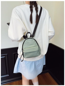 Rear view of a mint green mini backpack with adjustable black straps worn by a model