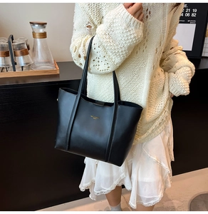 Dettaglio elegante borsa tote in pelle nera con scritte dorate minimaliste e spalline