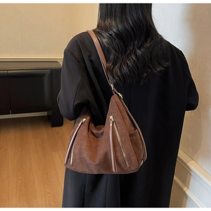 Detail view of deep brown suede-like hobo bag with dual metal zippers and long tassel puller