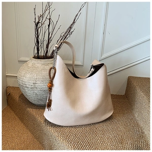 Close-up of cream-colored hobo bag with wrinkled leather texture and wooden bead charm