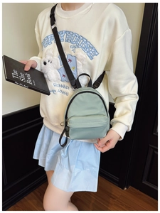 Detail of light green nylon mini backpack with adjustable strap held by a model