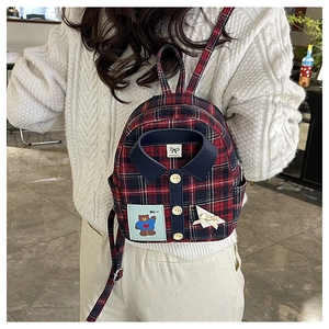 Detail of plaid tote bag featuring shirt collar design with bear patch and golden buttons