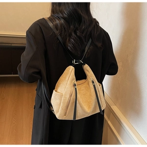 Rear view of a model wearing a beige suede backpack with dual vertical zipper pockets