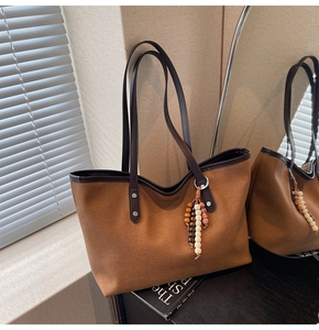 Detail of retro canvas tote bag with brown leather handles and wooden bead tassel