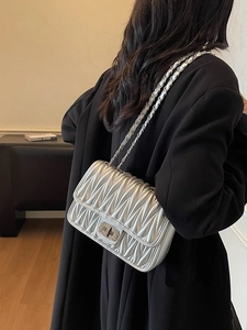 Silberne Stepptasche mit Metallkettenriemen und Drehverschluss am Model präsentiert