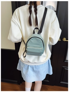 Detailed back view of a mint green mini nylon backpack worn as a stylish crossbody bag