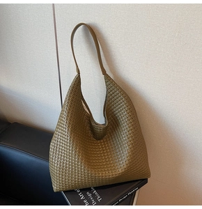 Macro detail of olive green woven leather tote bag texture resting on design books