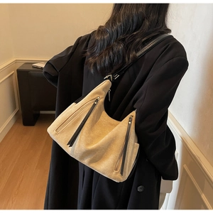 Detail showing beige suede hobo bag with distinctive black long leather zipper pullers