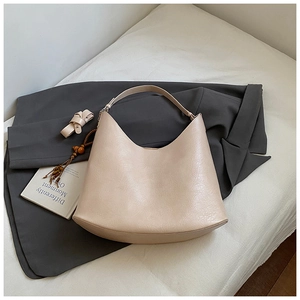 Detail of beige faux leather hobo bag with wood bead tassel on charcoal blazer