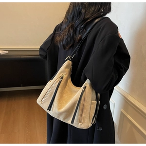 Detail of vintage beige suede shoulder bag with multiple zippers and black leather straps