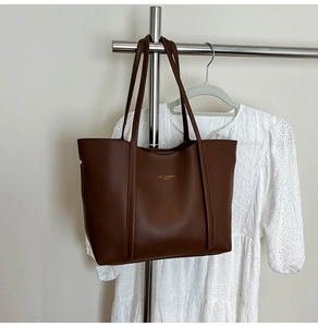 Dettaglio della borsa tote marrone scuro con trama in pelle pregiata e logo dorato