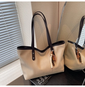 Detail of beige canvas tote with brown leather trim and bohemian beaded tassel detail