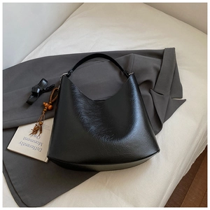 Detail of black pebbled leather hobo bag with ethnic tassel and wooden bead charm