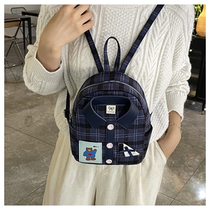 Detail view of mini plaid backpack with unique shirt-style collar, buttons, and bear patch