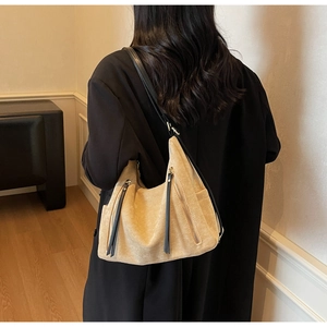 Detail of a large vintage beige suede shoulder bag with dual vertical black zipper pulls