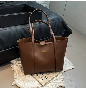 Dettaglio ravvicinato della borsa tote in ecopelle marrone con elegante logo dorato