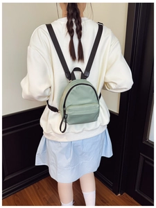 Rear view of a light green mini nylon backpack worn by a model for size and scale