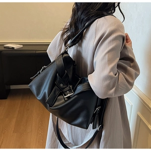 Black lychee leather tote bag showing drape and silver buckle in street style wear
