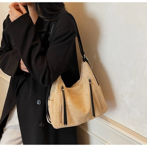 Detailed macro view of beige suede hobo bag with black leather straps and double zippers