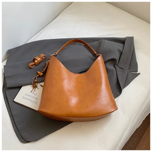 Close-up of brown faux leather hobo bag with wide shoulder strap and beaded tassel detail