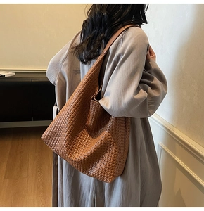 Detail of caramel brown woven leather tote bag texture and soft hobo shape on model