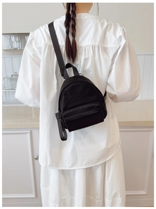 Minimalist black nylon backpack on a model showing the compact size and sleek design