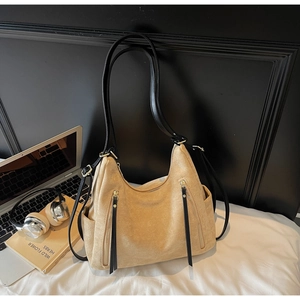 Detail of light camel suede hobo bag with dual black straps and long zipper pulls
