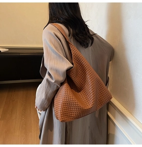 Detail of caramel brown woven leather tote bag shown on a model in a minimalist studio
