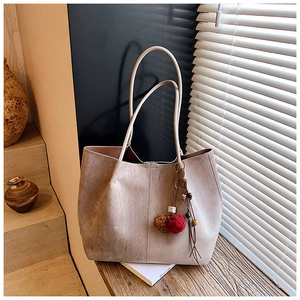 Detail of apricot suede tote bag featuring colorful faux fur pompom fringe charm
