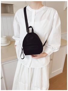 Mini black nylon backpack worn as a stylish crossbody chest bag for travel and leisure
