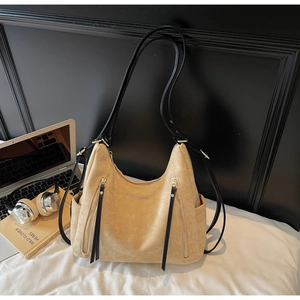 Close-up of beige suede shoulder bag with vertical zipper tassels and side pockets