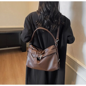 Detailed view of brown lychee grain leather tote bag with stylish metal buckle detail