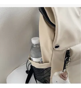Detail of nylon backpack side mesh pocket with drawstring and cute teddy bear charm