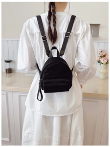 Detailed back view of a black mini nylon backpack worn by a model in a modern interior