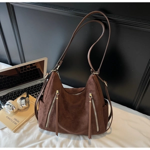 Detail of large dark brown suede tote bag with double zippers and metal accents