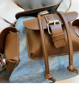 Close-up of contrast stitching on blue denim and brown leather patchwork backpack detail