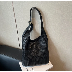 Détail de la texture tressée du sac seau noir avec boucle dorée et bandoulière réglable