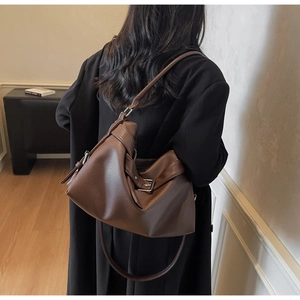 Detail of deep brown lychee grain leather tote bag with stylish buckle and long strap