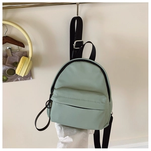 Detail view of mini mint green nylon backpack with black zipper and adjustable straps
