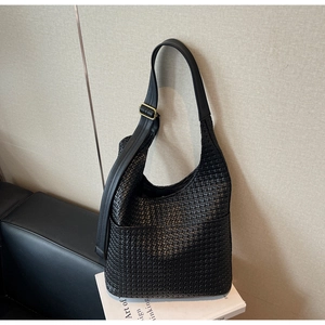 Détail d'un sac hobo noir tressé avec bandoulière réglable et boucle dorée mate