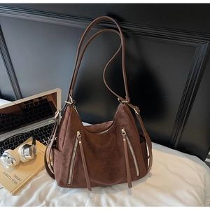 Detail of dark brown suede Hobo bag with vertical zipper accents in a modern lifestyle setting