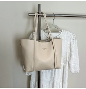 Dettaglio ravvicinato della borsa tote in pelle PU crema con logo e finitura liscia