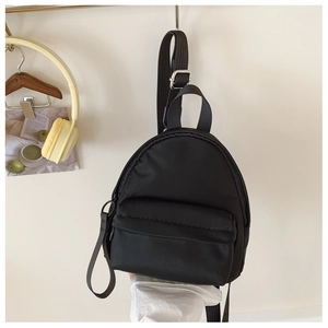 Close-up of black mini nylon backpack with adjustable straps and front zipper pocket