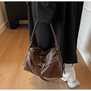 Close-up of a dark brown lychee-patterned tote bag with a metallic buckle detail