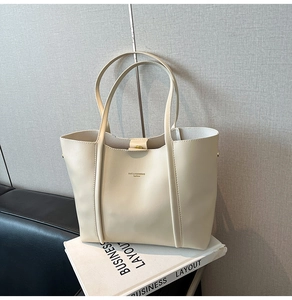 Dettaglio borsa tote in pelle beige con chiusura magnetica e manici sottili eleganti